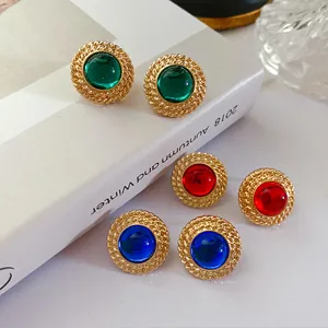 Vue rapprochée de boucles d'oreilles vintage dorées avec pierres vertes, rouges et bleues.
