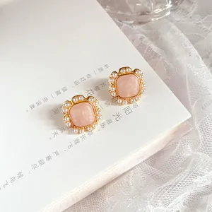 Macro view of vintage French pearl earrings with peach enamel center on book page