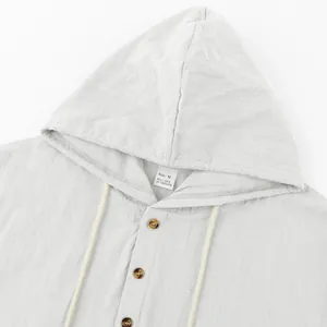 Close-up of a white linen hooded Henley shirt showing the collar label and brown buttons.