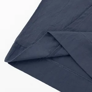 Close-up detail of the fine stitching and textured linen fabric on the shirt hem.