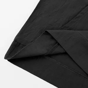 Close-up of black linen shirt hem showing detailed stitching and fabric texture