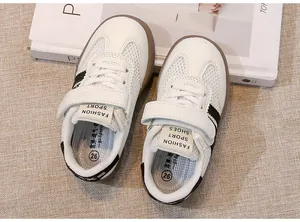 Nahaufnahme von weißen Kinder-Sportschuhen aus Mesh mit schwarzen Streifen.