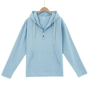 Detail of light blue linen-like hooded Henley shirt with buttons and front pocket