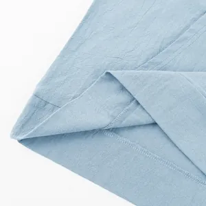 Close-up of neat stitching and breathable linen fabric texture on light blue Henley shirt.