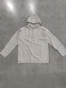 Close-up detail of men's loose linen hooded Henley shirt with buttons and pocket