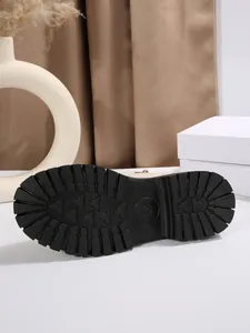 Gros plan sur l'épaisse semelle crantée noire et les motifs d'un botte Martin pour femme