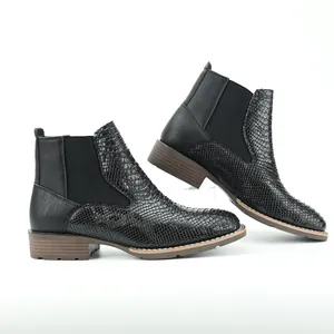 Close-up of black snakeskin embossed Chelsea boots for men with elastic side panels.
