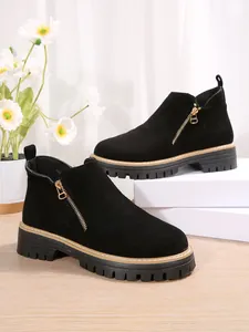 Vue détaillée de bottines stylées en daim noir à talons épais avec fermeture éclair dorée