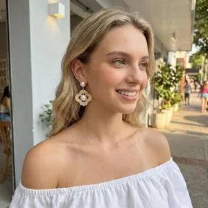 Gros plan détaillé de boucles d'oreilles fleurs en perles rétro portées par un mannequin.