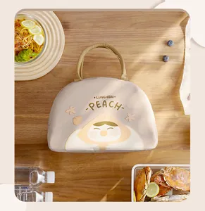 Insulated handheld lunch bag featuring a cute cartoon peach character on a wooden table