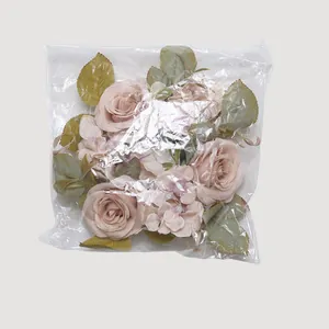 Corona de rosas y hortensias artificiales en una bolsa de plástico transparente