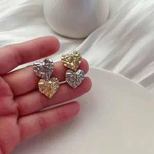 Detail of two-tone crumpled heart earrings with a unique textured metallic finish