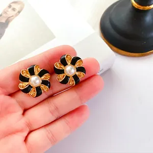 Vue détaillée de boucles d'oreilles baroques avec émail noir et perle centrale