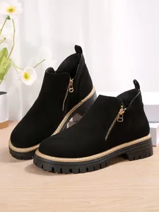 Vue détaillée de bottines en daim noir avec fermeture éclair dorée et semelle crantée.