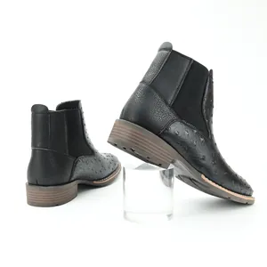 Close-up detail of men's black Chelsea boots with textured faux ostrich leather finish.