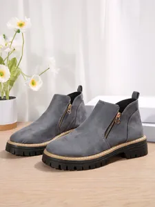 Bottines grises en suédine à talons épais avec fermeture éclair latérale et semelle crantée.