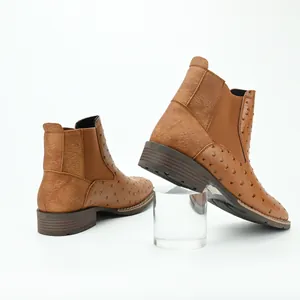 Detailed macro view of men's brown ostrich pattern Chelsea boots on white background