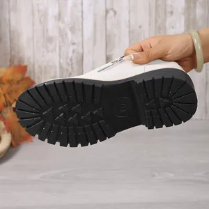 Detail of thick black lug sole on white round-toe loafer with side zipper