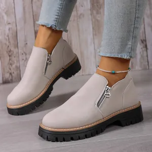 Close-up of women's light gray suede loafers featuring a side zipper and lug sole