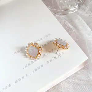 Close-up of vintage French style enamel earrings featuring elegant pearl borders.