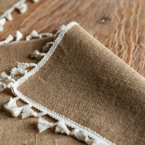 Close-up of rustic jute placemat with white tassel fringe detailing