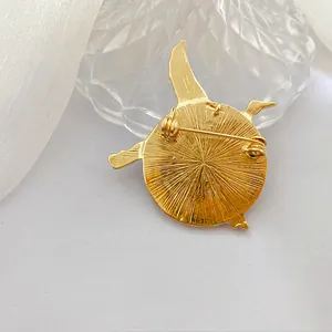 Detalle posterior de broche de grulla dorada vintage con textura y cierre de alfiler