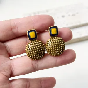 Detalle de pendientes vintage de esmalte con diseño de lunares dorados en relieve