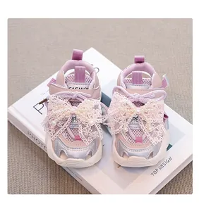 Close-up of pink girl's sporty sandals with elegant lace and pearl bow details.