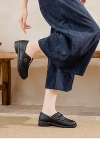 Model wearing black flat leather loafers for older women on casual denim pants.