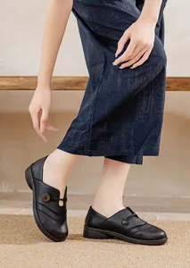 Detail view of comfortable black slip-on flat shoes for women with a decorative buckle design