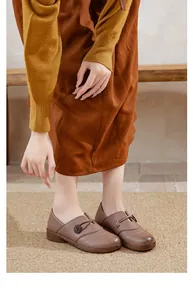 Detail showing brown slip-on flat shoes with decorative flower accent