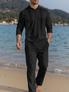 Men's casual black linen set featuring a hooded zipper top and matching pants on a beach