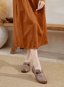 Close-up of brown leather slip-on flat shoes for elderly women in a warm indoor setting