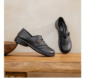 Macro view of black leather slip-on flat shoes featuring a decorative flower button