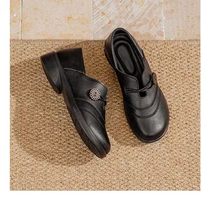 Overhead view of comfortable black slip-on flat shoes for elderly women on a textured mat