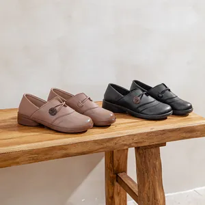 Comfortable slip-on flat loafers with soft soles for elderly women, displayed on wood
