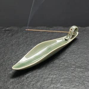 Portaincenso in ceramica celadon a forma di foglia su sfondo di pietra con fumo