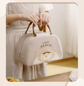 Close-up of cute cartoon insulated lunch bag with peach print being held by hand