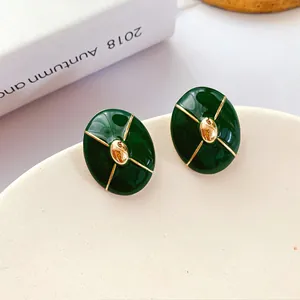 Close-up macro view of vintage dark green enamel stud earrings with gold accents
