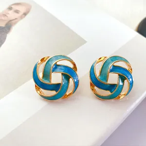 Detailed macro view of vintage gold hollow earrings featuring blue gradient enamel glaze