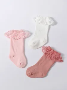Primer plano de calcetines altos con volantes de encaje para bebé en rosa y blanco