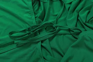 Detailansicht eines grünen rückenfreien Jumpsuits mit tiefem V-Ausschnitt und Kordelzug.