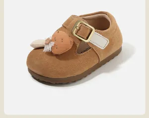 Close-up of brown suede baby walking shoe with decorative strawberry and gold buckle