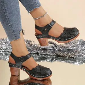 Elegant black laser-cut hollow sandals featuring a wooden block heel and ankle strap.