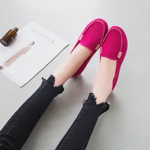 Dettaglio di mocassini in camoscio fucsia con fibbie dorate e jeans sfrangiati