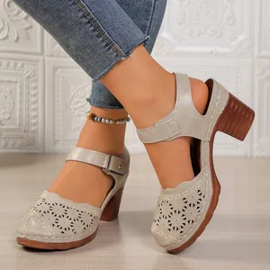 Detail view of beige chunky heel sandals with hollow-out design and buckle strap.