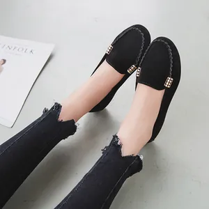 Eleganti mocassini in camoscio nero con fibbie dorate e jeans sfrangiati di moda