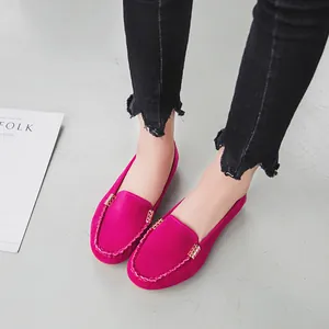 Primo piano di mocassini fucsia in pelle scamosciata indossati con jeans neri