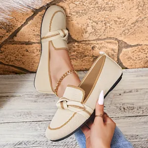 Gedetailleerde close-up van beige gebreide loafers voor dames met strik en contrastrand.