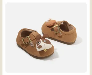 Close-up of brown suede toddler shoes with cute dog pattern and buckle